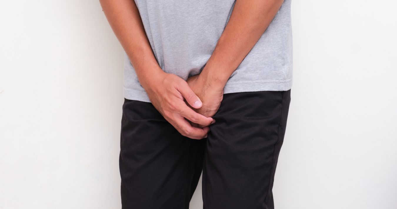 A man holding his hands over his groin.