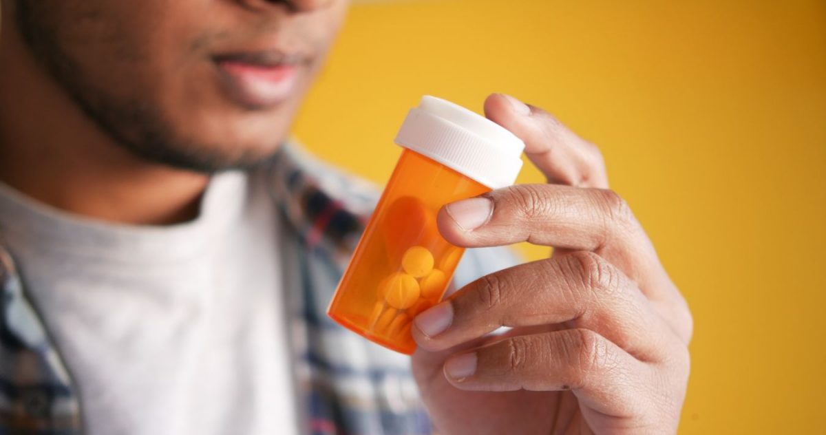 A man holding a bottle of pills.